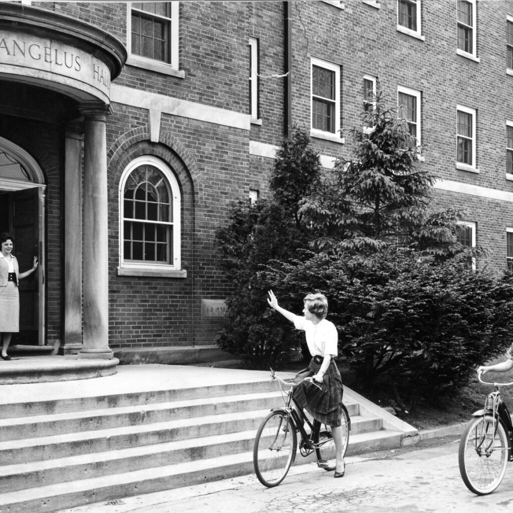 Students on bicycles outside Archangelus Hall 1950s,